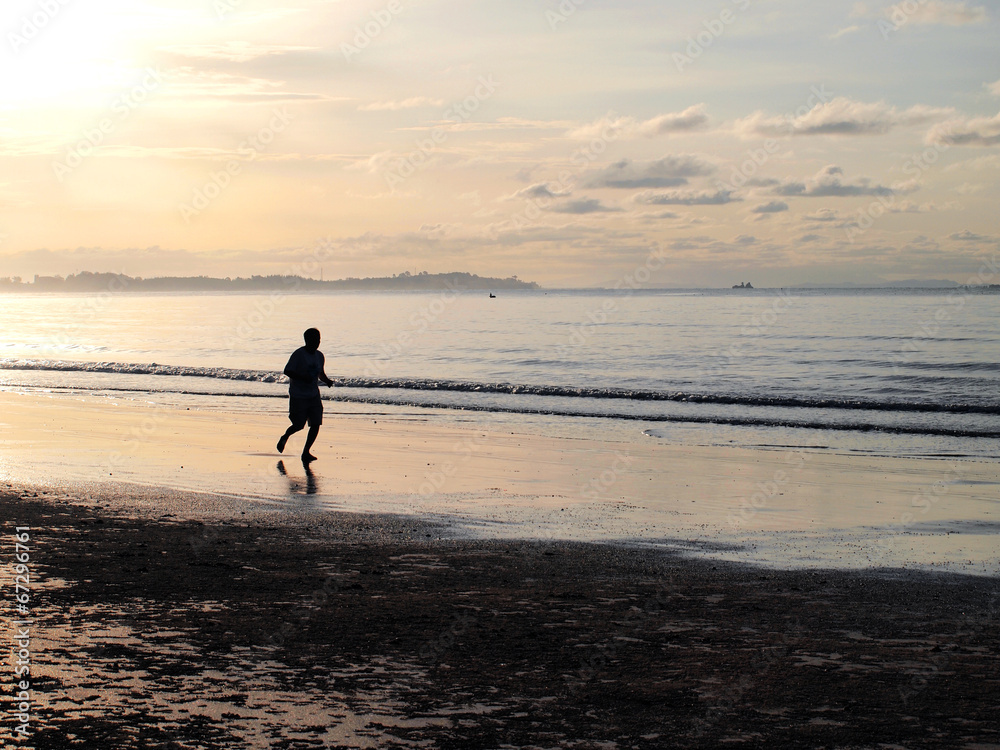 Silhouette of a man running in the beach during sunset