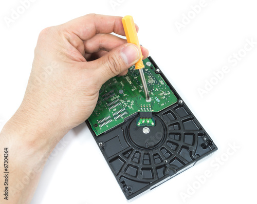 hand with screwdriver repairing hard drive or hard disc