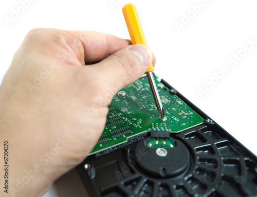 hand with screwdriver repairing hard drive or hard disc