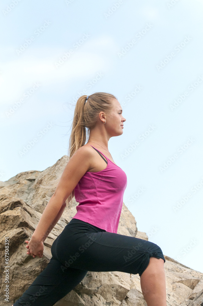 Fitness. Young woman training on a mountain