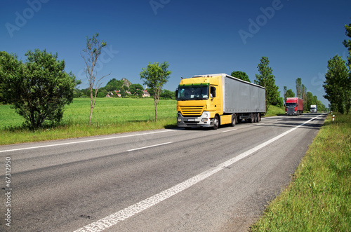 Obraz na płótnie Road lined with trees, three passing trucks w salonie
