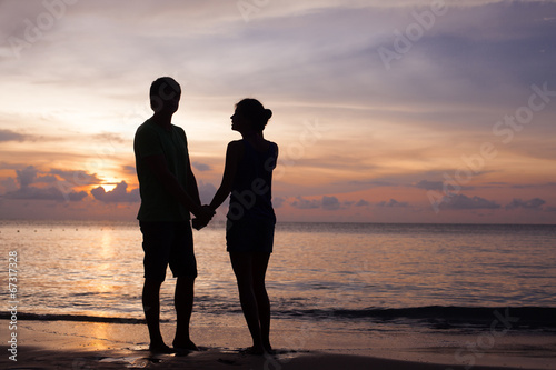 sunset silhouette of young couple in love at beach