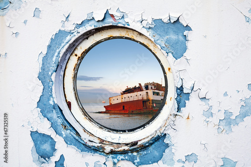 Ship wreck behind round porthole in white and blue wall