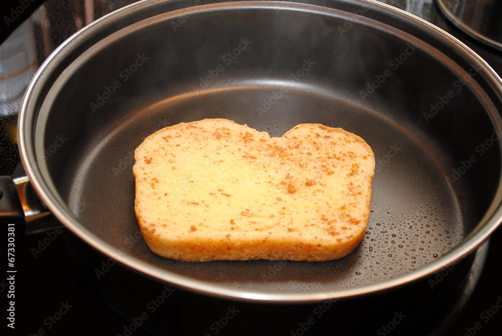 A Sliceof Raw French Toast Cooking in a Fry Pan