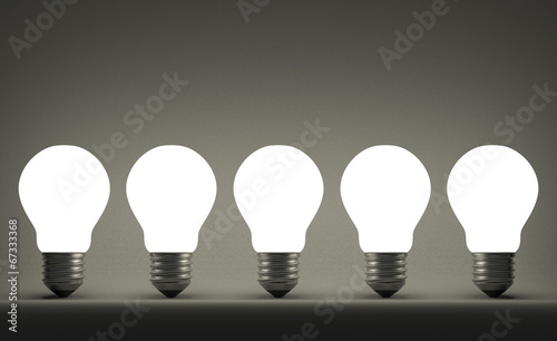 Row of glowing tungsten light bulbs on gray