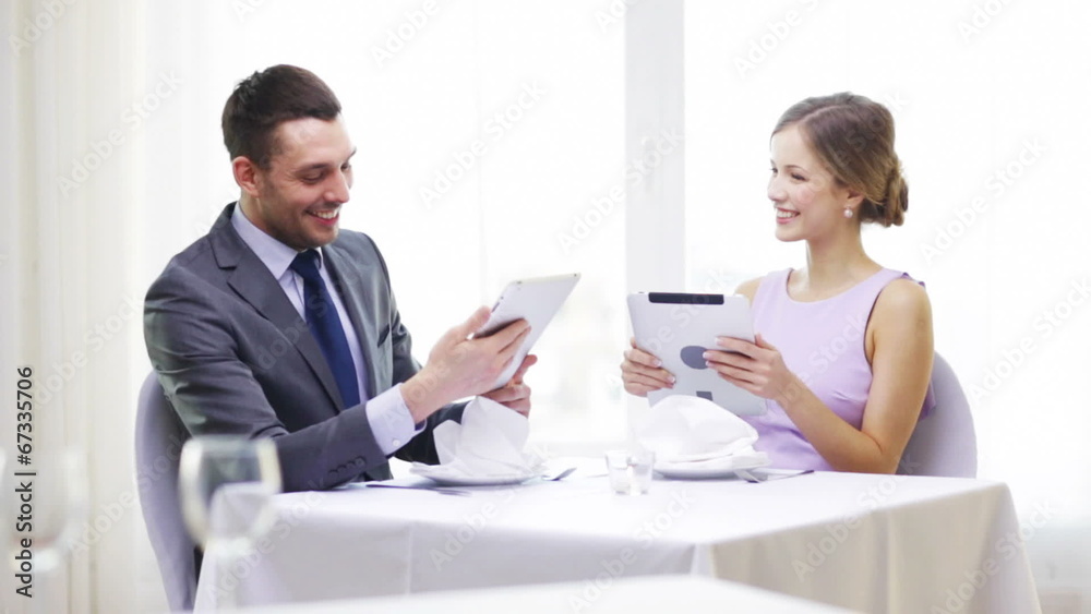 couple with menus on tablet pc at restaurant couple with menus on tablet pc at restaurant