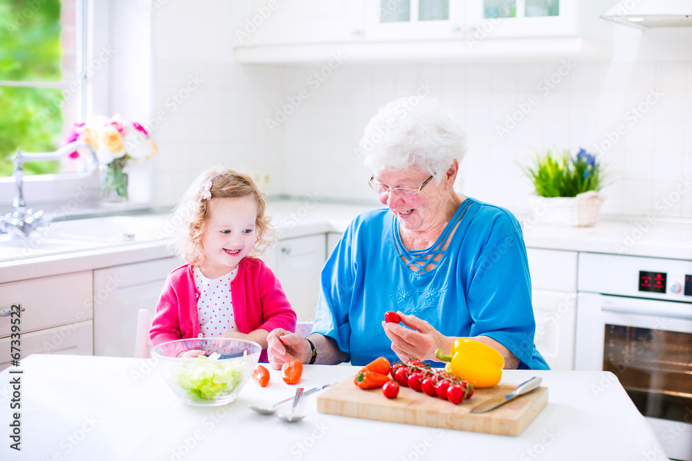 Adorable grandmother and little girl making salad