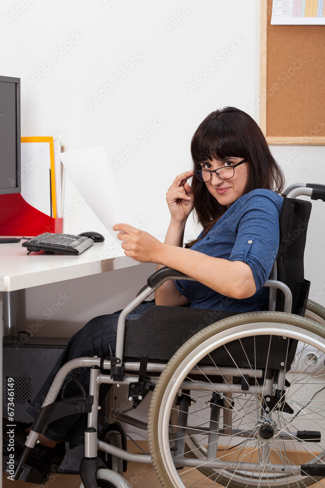 Disabled young girl on wheelchair working in her office