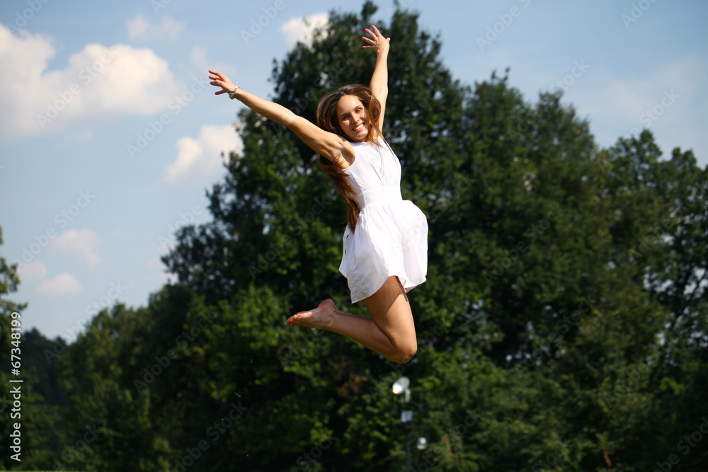 Happy young woman jumping in white dress