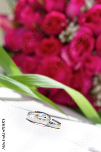 wedding rings and bridal bouquet over white photo