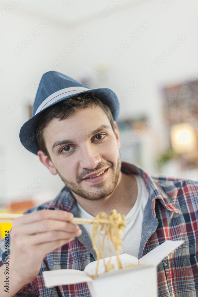  portrait of a young man  eating Chinese noodles with chopsticks