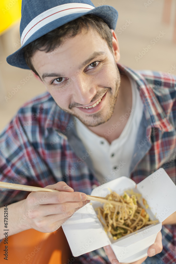 portrait of a young man eating Chinese noodles with chopsticks portrait of a young man eating Chinese noodles with chopsticks