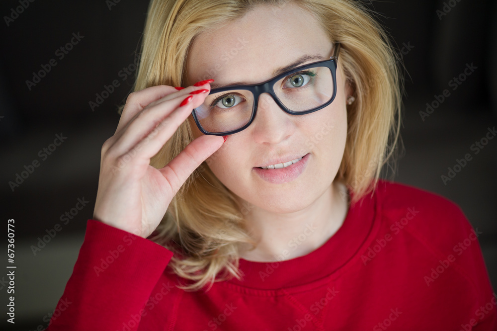 Portrait of beautiful young woman in glasses on dark background