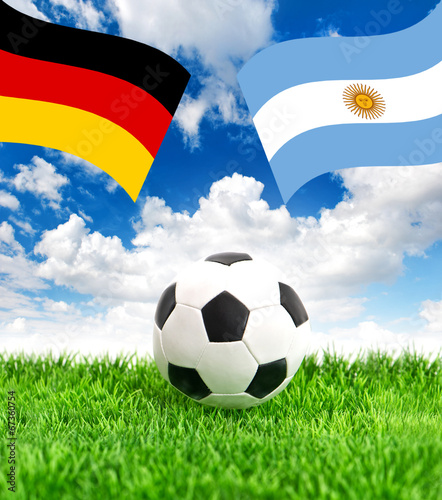 Soccer ball on grass and flags of Germany and Argentina