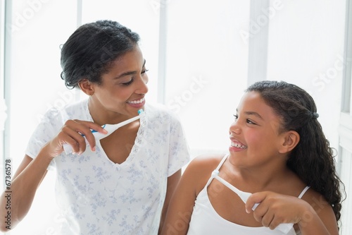 Pretty mother brushing her teeth with her daughter