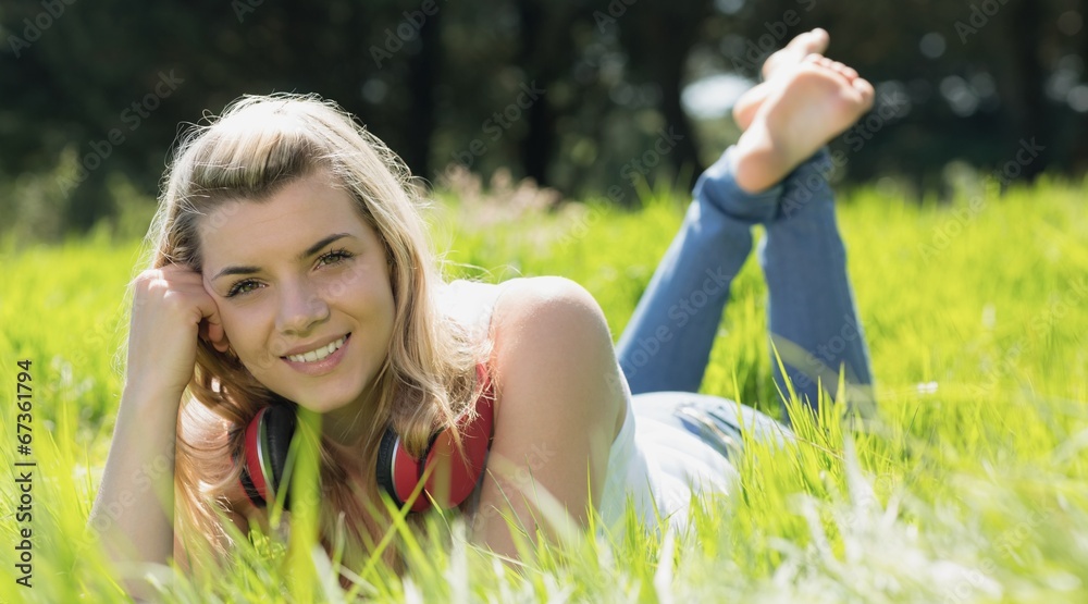 Pretty blonde lying on grass with headphones around neck Pretty blonde lying on grass with headphones around neck