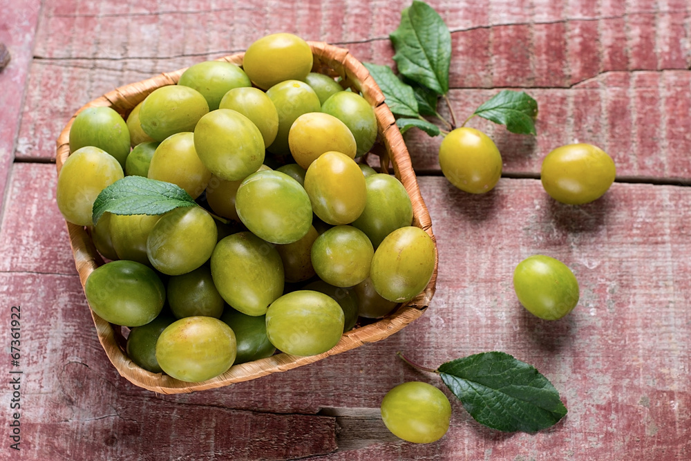 Yellow plums in a basket on wooden background