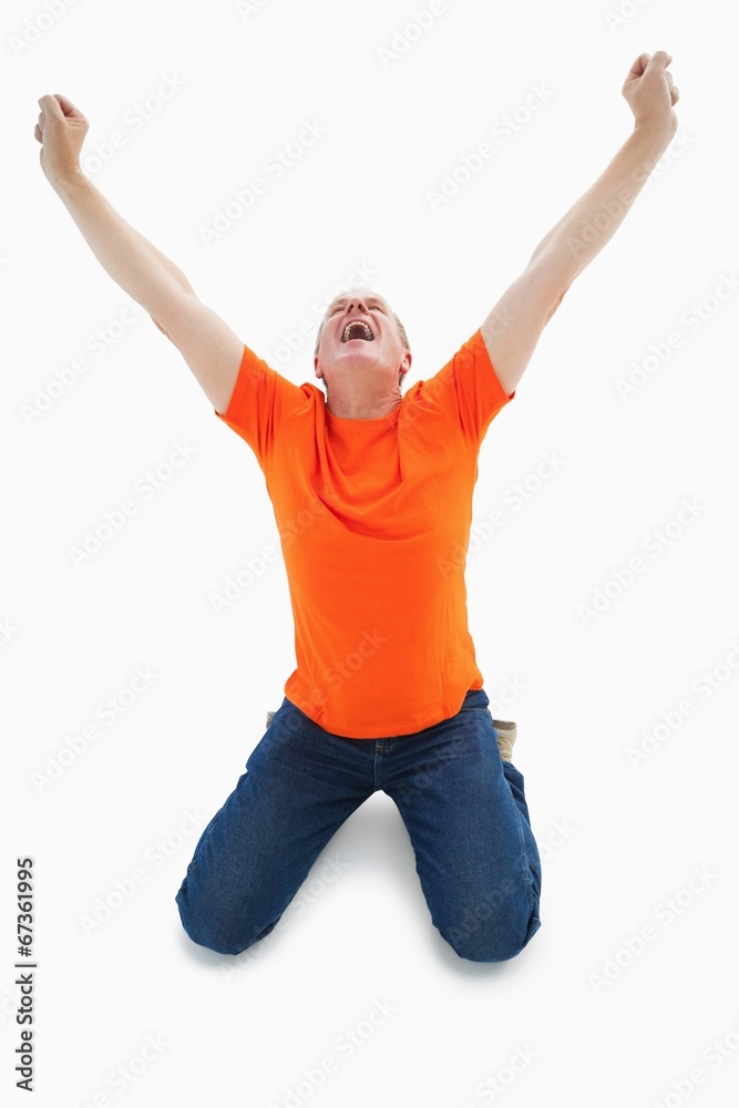 Mature man in orange tshirt cheering while kneeling Mature man in orange tshirt cheering while kneeling