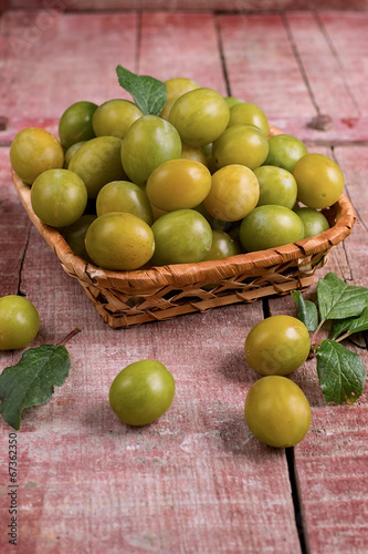 Yellow plums in a basket on wooden background