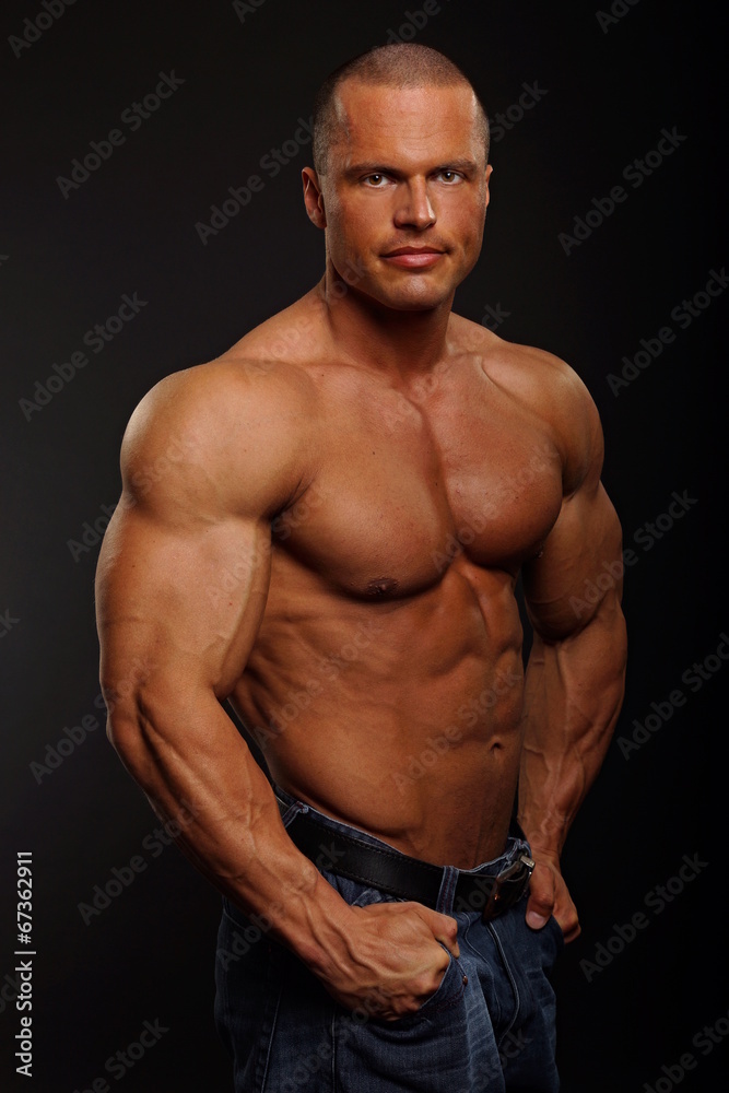 Fototapeta premium Handsome muscular man poses on gray background
