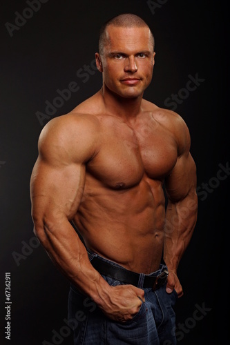 Handsome muscular man poses on gray background
