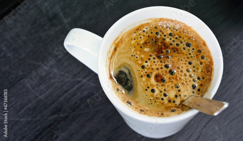 Foto Top view to the white cup with brown coffee and spoon.