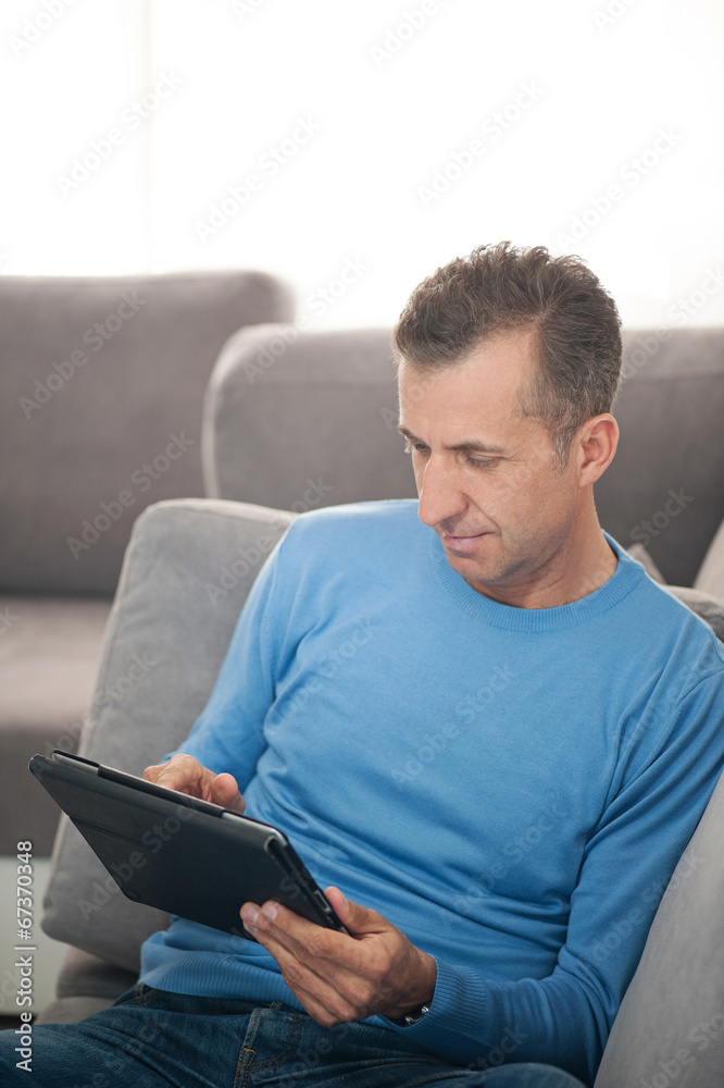Happy man relaxing on sofa with digital tablet - vertical Happy man relaxing on sofa with digital tablet - vertical