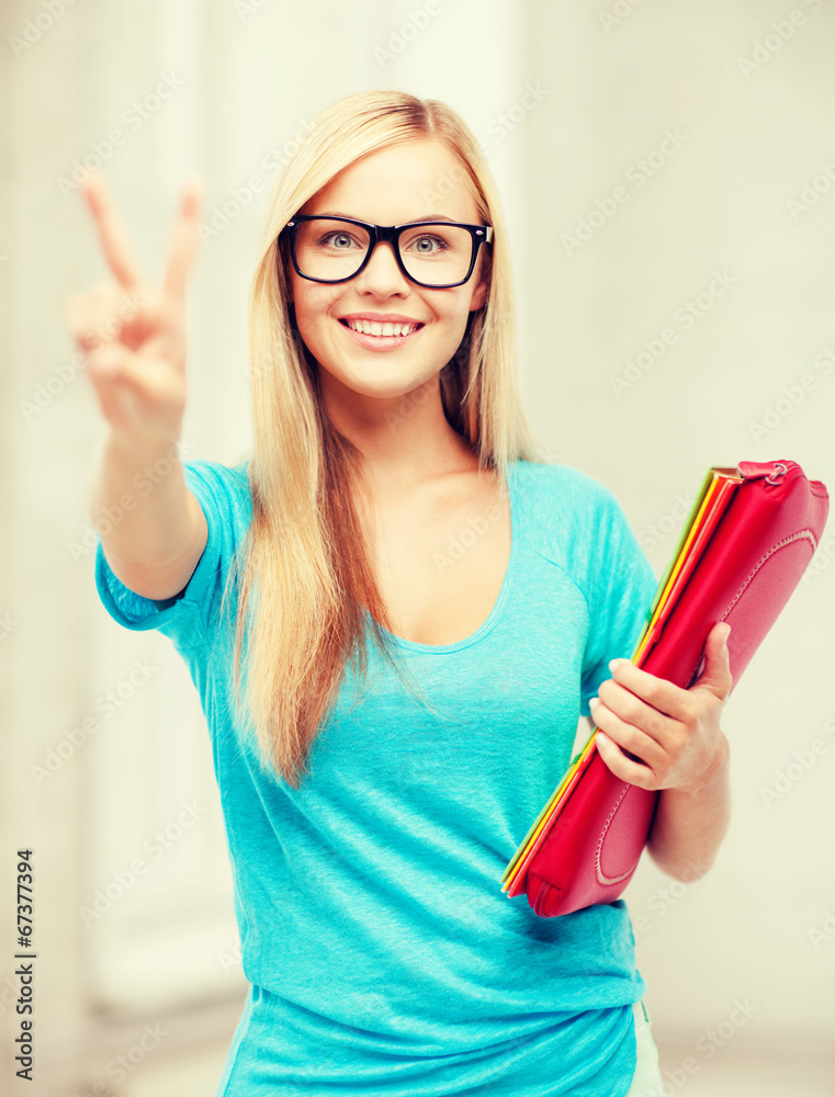 smiling student with folders showing victory sign smiling student with folders showing victory sign