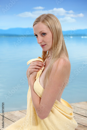 Dziewczyna, blondynka w ręczniku kąpielowym nad jeziorem.