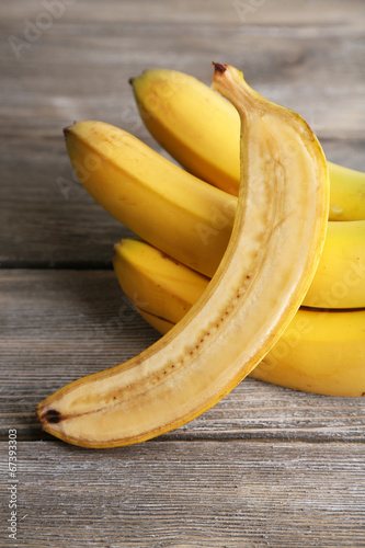 Halved and whole ripe bananas on wooden background