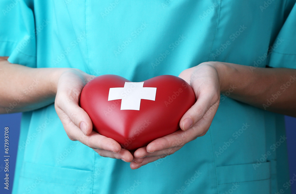 Red heart with cross sign in doctor hand, close-up, - obrazy, fototapety, plakaty 