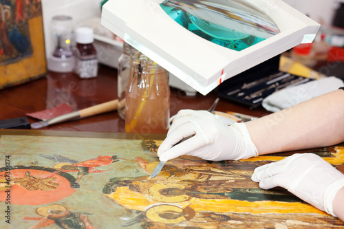 Closeup of  Restorer working on the old icon photo