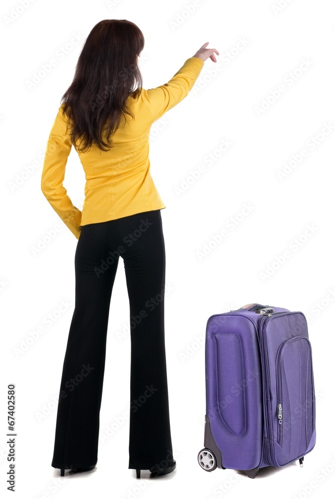 Young traveling woman with suitcas points at wall. Young traveling woman with suitcas points at wall.