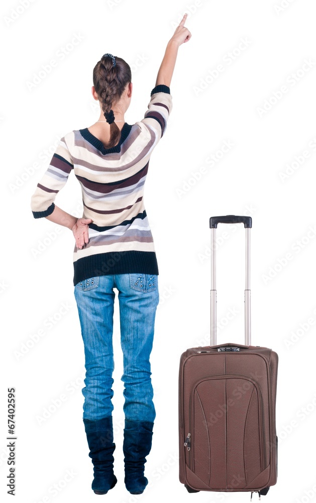 traveling young woman with suitcas pointing at wall. traveling young woman with suitcas pointing at wall.