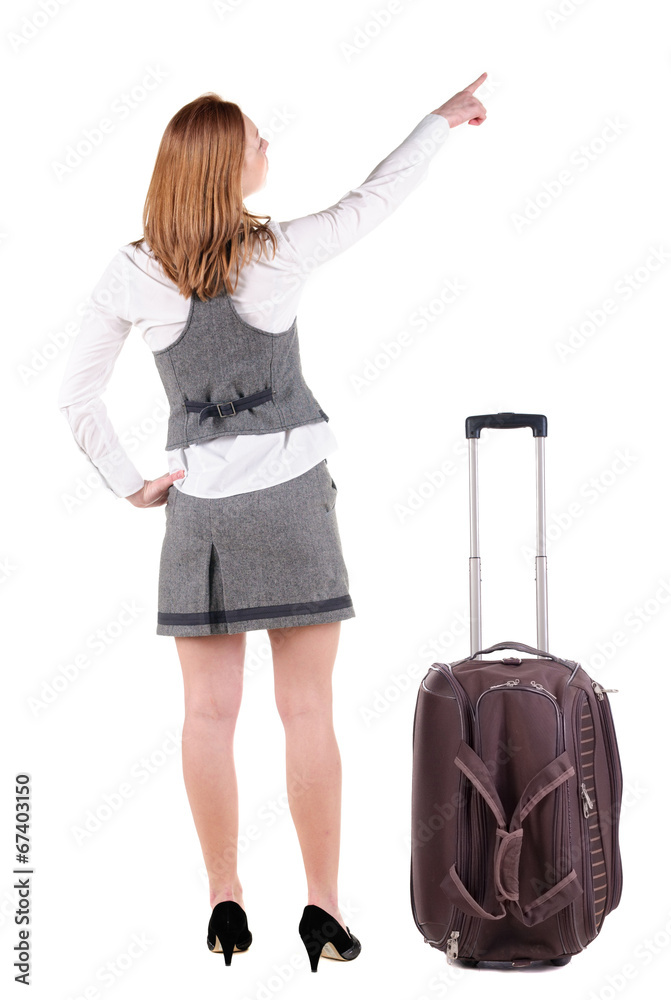 Beautiful young woman in dresstraveling with suitcas and pointin Beautiful young woman in dresstraveling with suitcas and pointin
