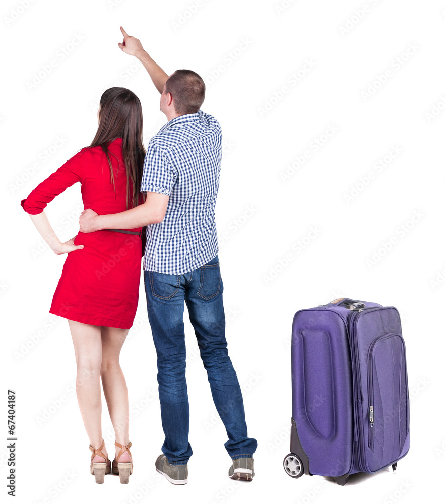 young couple traveling with suitcas and pointing at wal Back vie young couple traveling with suitcas and pointing at wal Back vie