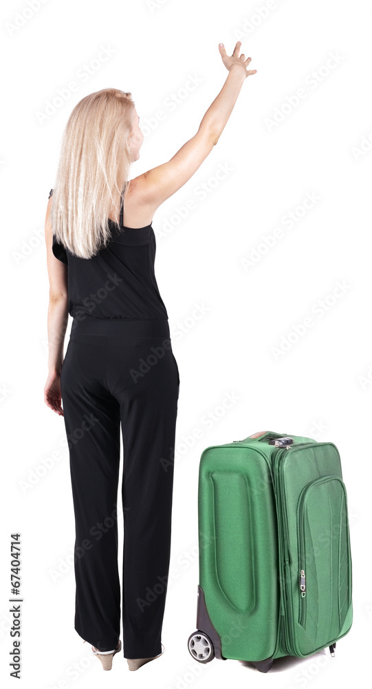Back view of young blonde woman traveling with suitcas and point Back view of young blonde woman traveling with suitcas and point