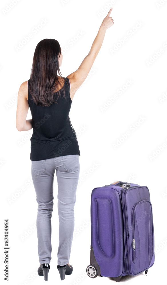Back view of young brunette woman traveling with suitcas and poi Back view of young brunette woman traveling with suitcas and poi
