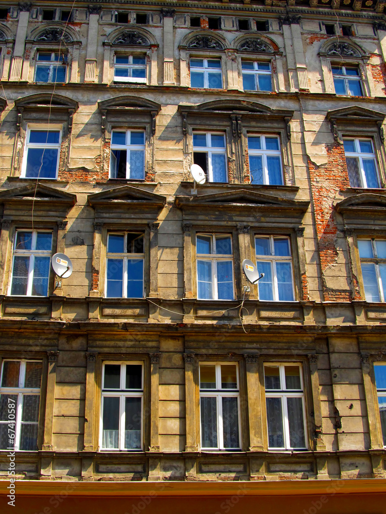 wall with windows of an old, damaged residential building in Wro
