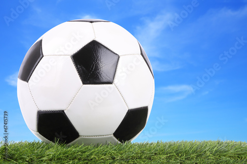 Stitch leather soccer ball on field blur blue sky.