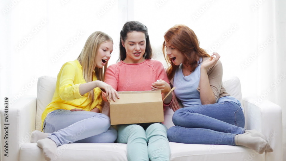 smiling teenage girls opening cardboard box smiling teenage girls opening cardboard box