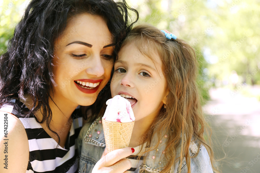 Happy mom and daughter in the green park with ice cream Happy mom and daughter in the green park with ice cream