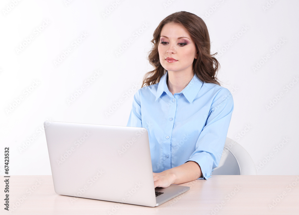 Young business woman sitting at table with notebook in room Young business woman sitting at table with notebook in room