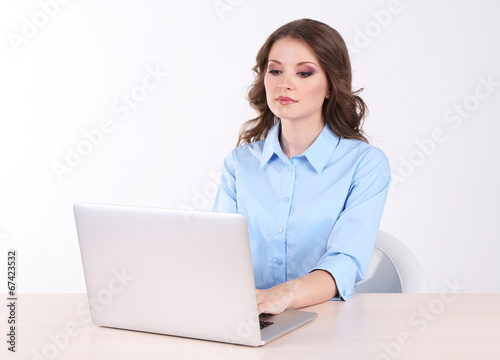Young business woman sitting at table with notebook in room © Africa Studio