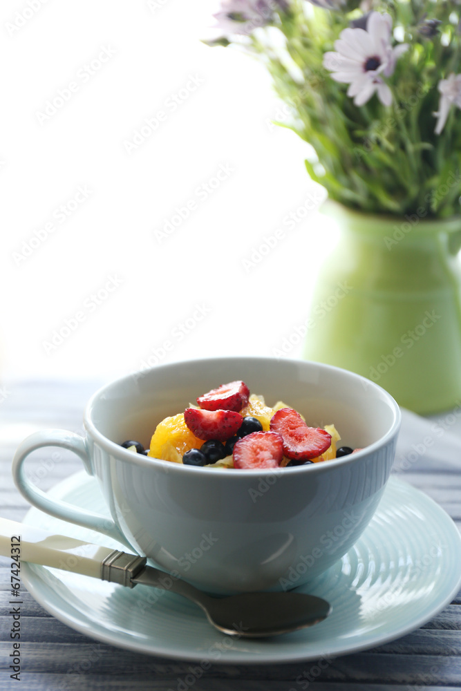 Useful homemade fruit salad and flowers on table