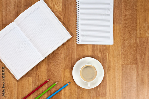 Blank notepad with office supplies and cup of coffee on wooden t