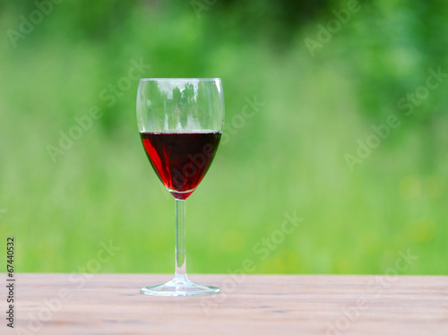 Glass of wine on green nature background.