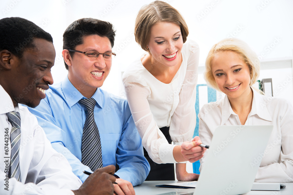 Happy business people gathered around laptop Happy business people gathered around laptop