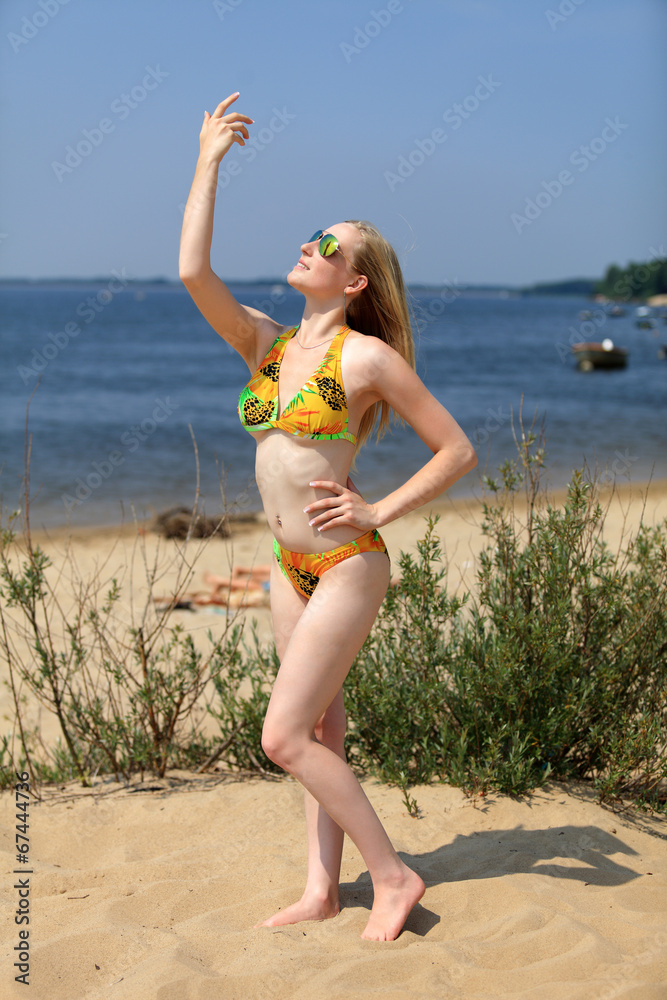 Naklejka premium Dziewczyna, blondynka na plaży w stroju kąpielowym.