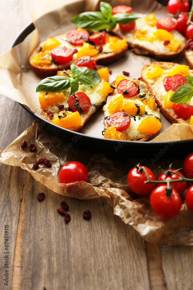 Tasty bruschetta with tomatoes on pan, on old wooden table Tasty bruschetta with tomatoes on pan, on old wooden table